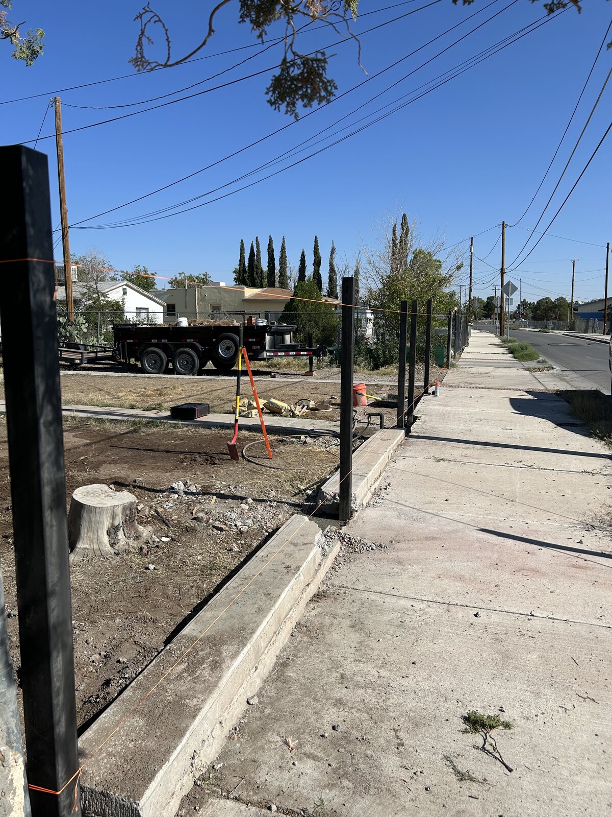 Black steel fence posts set in concrete along a front yard sidewalk