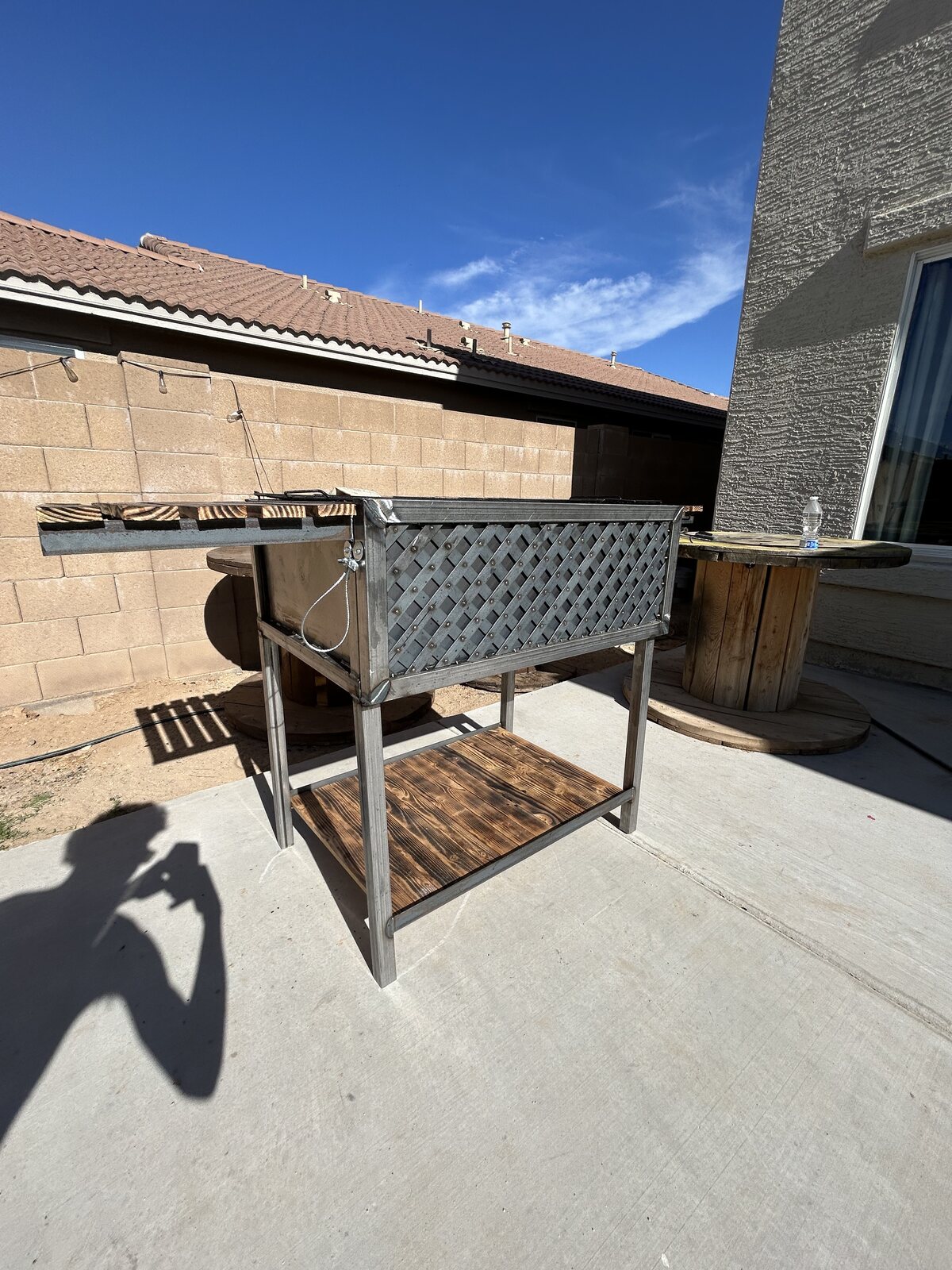 Custom steel Santa Maria grill cart with torched wood shelves on a patio